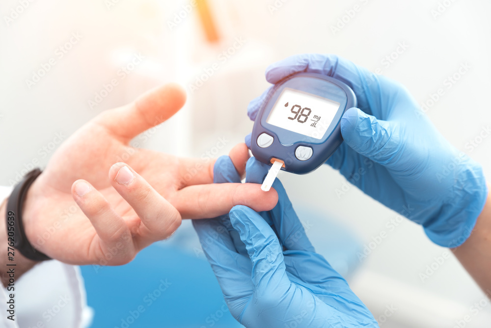 Doctor checking blood sugar level with glucometer Doctor checking blood sugar level with glucometer